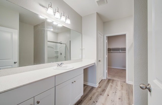 bathroom with visible vents, a stall shower, wood finished floors, baseboards, and vanity