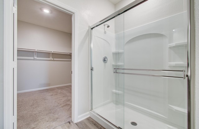 full bathroom featuring baseboards, a spacious closet, and a shower stall