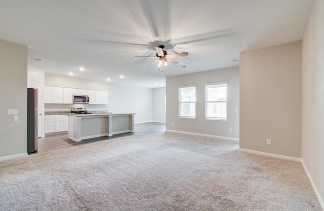 kitchen featuring open floor plan, light colored carpet, and appliances with stainless steel finishes