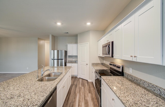 kitchen with visible vents, appliances with stainless steel finishes, wood finished floors, white cabinetry, and a sink