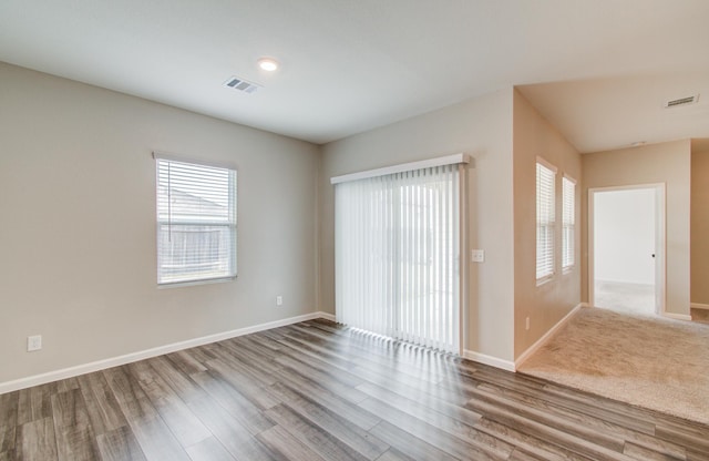 unfurnished room with wood finished floors, visible vents, and baseboards