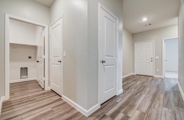 corridor featuring light wood-style flooring, baseboards, and visible vents