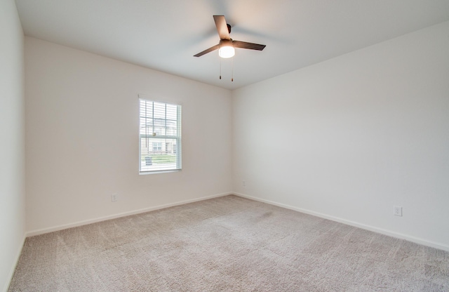 carpeted empty room featuring baseboards and a ceiling fan