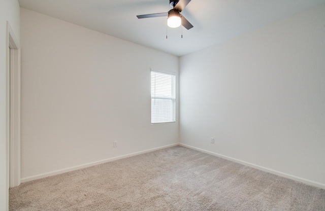 spare room with light colored carpet, baseboards, and ceiling fan