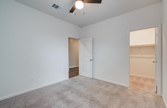 unfurnished bedroom featuring visible vents, light carpet, baseboards, and a spacious closet