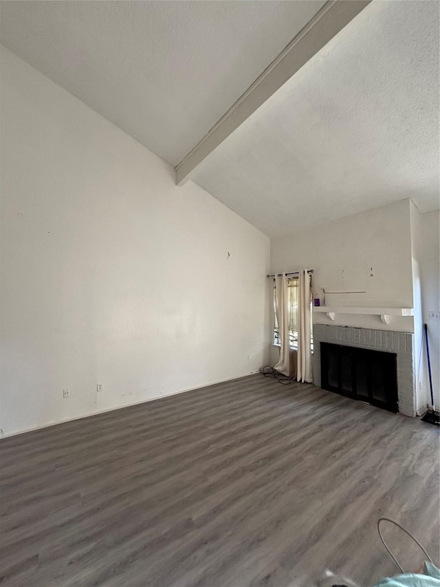 unfurnished living room featuring a brick fireplace, a textured ceiling, lofted ceiling with beams, and wood finished floors