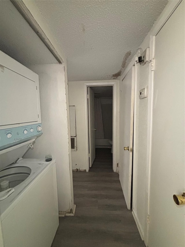 laundry area with laundry area, stacked washer and clothes dryer, a textured ceiling, and dark wood-type flooring