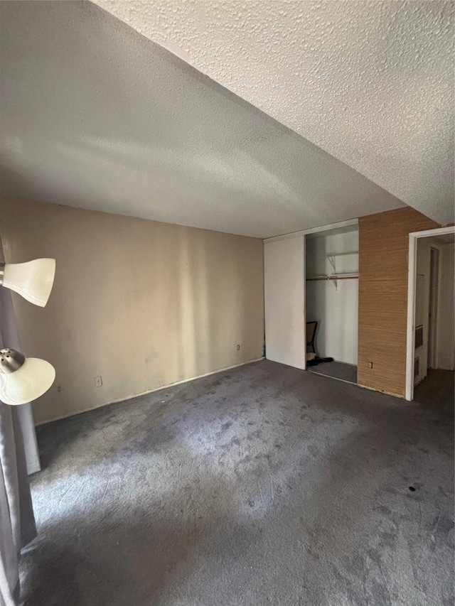 unfurnished bedroom with a closet, dark carpet, and a textured ceiling