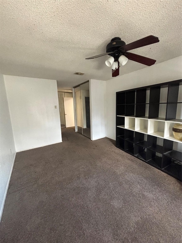 unfurnished living room with visible vents, a textured ceiling, carpet flooring, and a ceiling fan