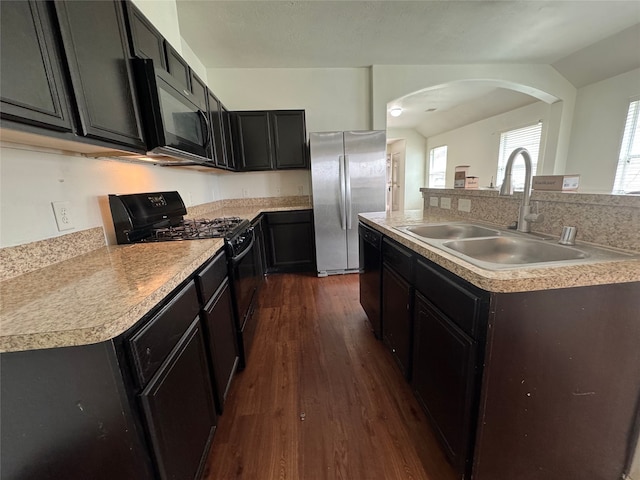 kitchen featuring light countertops, vaulted ceiling, dark wood-style floors, black appliances, and a sink