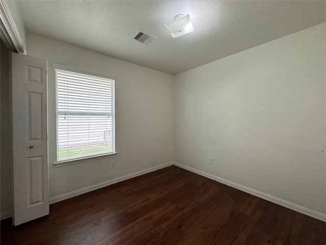 unfurnished room with dark wood finished floors, baseboards, and visible vents