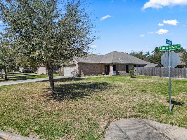 view of front of property featuring driveway, fence, a front yard, an attached garage, and brick siding