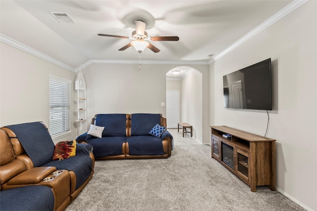 living area with visible vents, light carpet, ornamental molding, arched walkways, and ceiling fan