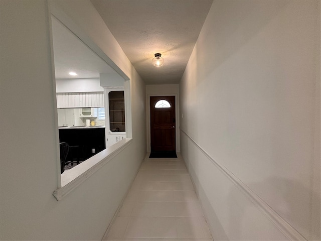 corridor featuring light tile patterned floors and a textured ceiling