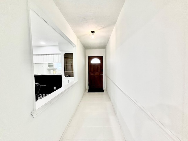 corridor featuring light tile patterned floors and a textured ceiling