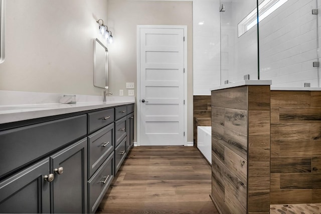 full bathroom with vanity, wood finished floors, a tub to relax in, and a tile shower