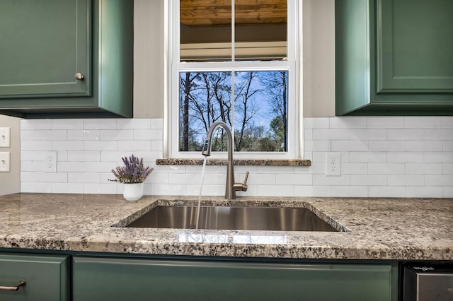 details featuring decorative backsplash, green cabinets, and a sink