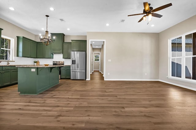 kitchen with a wealth of natural light, a breakfast bar, backsplash, stainless steel fridge with ice dispenser, and green cabinetry
