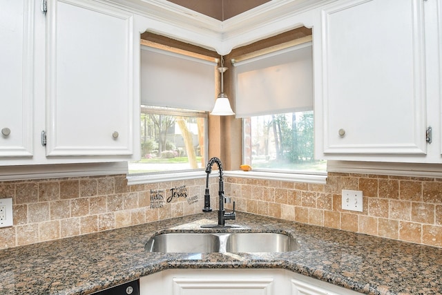 kitchen featuring tasteful backsplash, dark stone countertops, white cabinets, and a sink