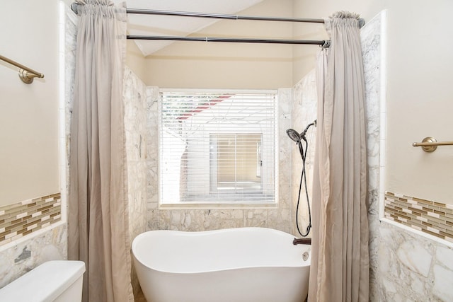 full bathroom with toilet, a freestanding bath, tile walls, and curtained shower