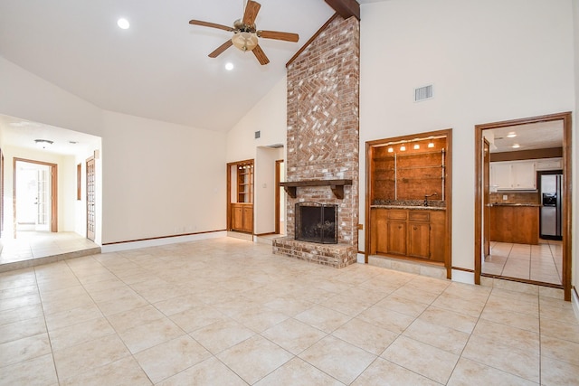 unfurnished living room featuring light tile patterned floors, a ceiling fan, visible vents, vaulted ceiling with beams, and a brick fireplace