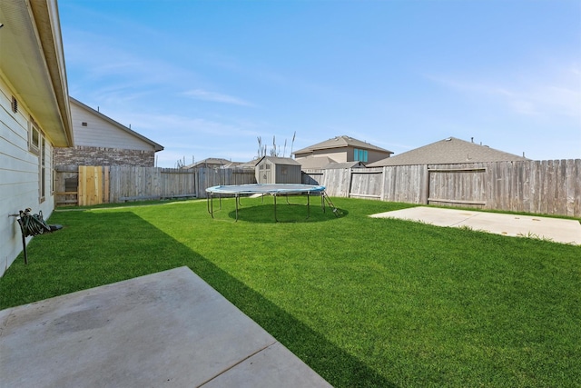 view of yard featuring a storage unit, a trampoline, a fenced backyard, an outdoor structure, and a patio area