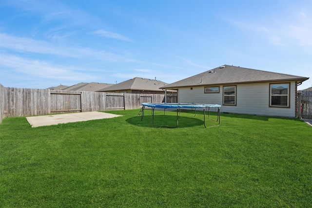 view of yard featuring a trampoline, a fenced backyard, and a patio area