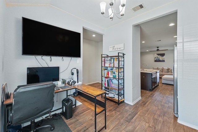 office with visible vents, ceiling fan with notable chandelier, a sink, wood finished floors, and baseboards