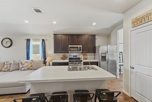 kitchen featuring dark brown cabinetry, open floor plan, light countertops, stainless steel appliances, and a sink