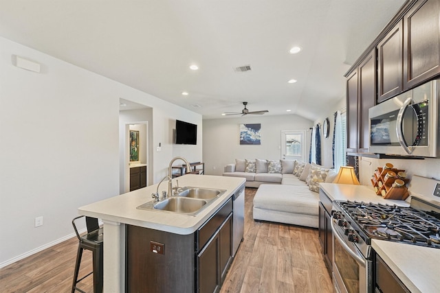 kitchen featuring a sink, stainless steel appliances, dark brown cabinets, and light wood-style flooring