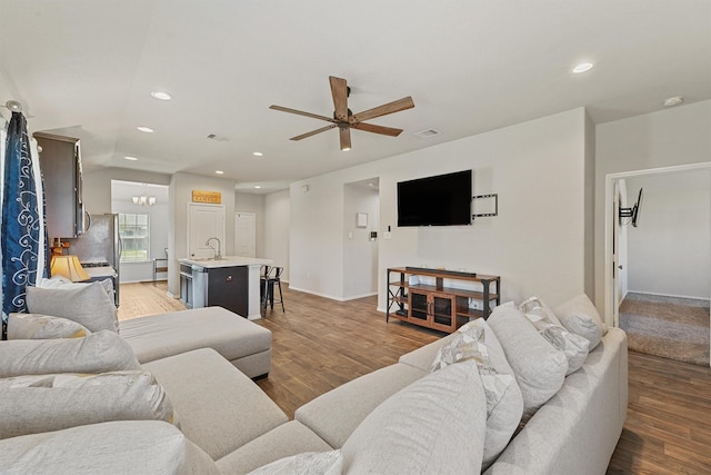 living area featuring light wood finished floors, recessed lighting, and ceiling fan with notable chandelier