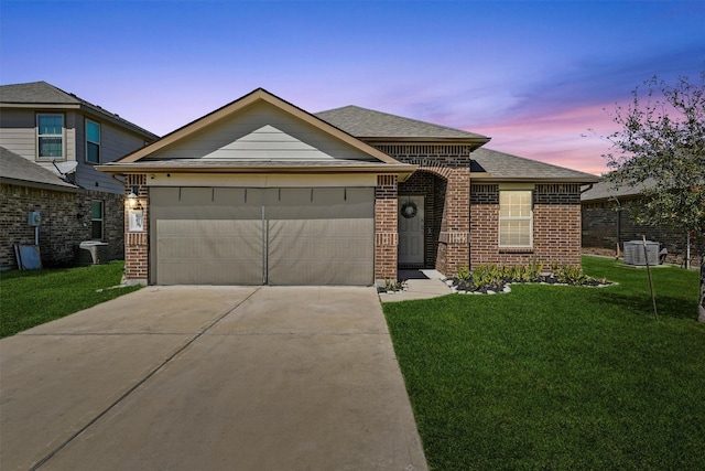 view of front of property featuring a front lawn, concrete driveway, an attached garage, a shingled roof, and brick siding