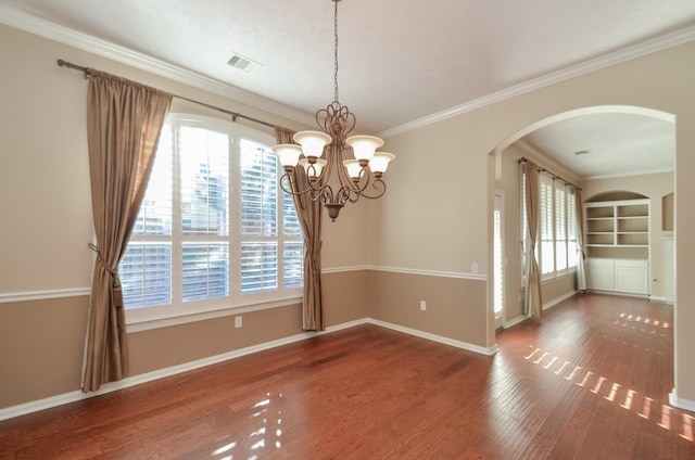 spare room featuring visible vents, baseboards, built in features, ornamental molding, and wood finished floors