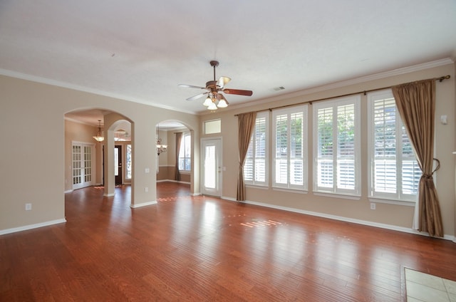 unfurnished living room with arched walkways, ornamental molding, baseboards, and wood finished floors