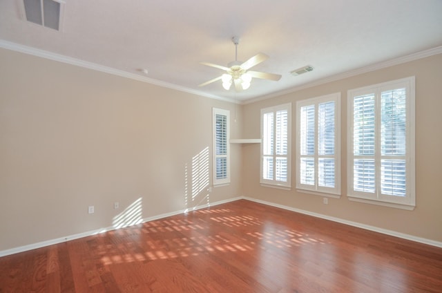 empty room featuring baseboards, wood finished floors, visible vents, and ornamental molding