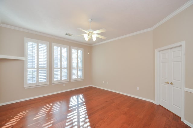 empty room with visible vents, plenty of natural light, crown molding, and wood finished floors