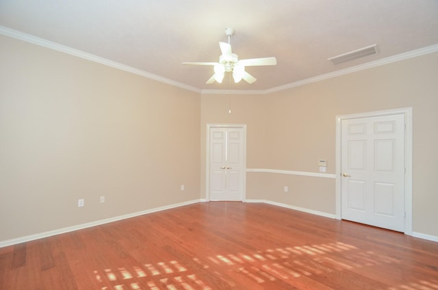 spare room featuring visible vents, baseboards, wood finished floors, and crown molding