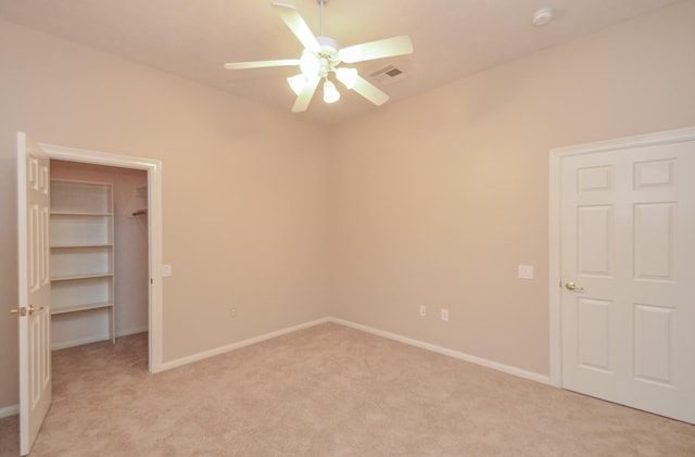 unfurnished bedroom with a spacious closet, visible vents, light colored carpet, and baseboards