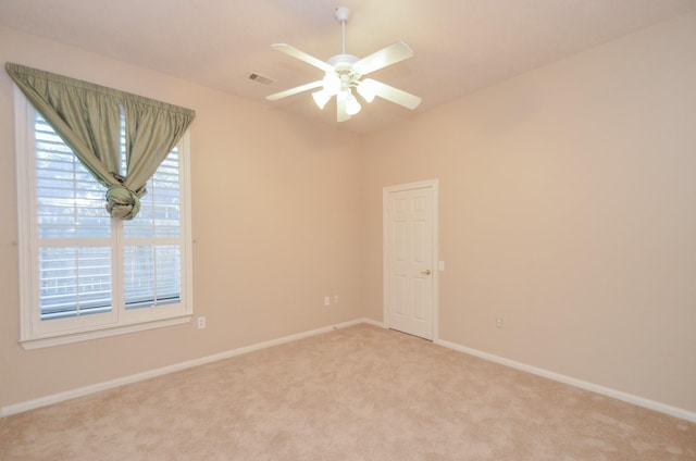 unfurnished room with visible vents, light colored carpet, baseboards, and ceiling fan