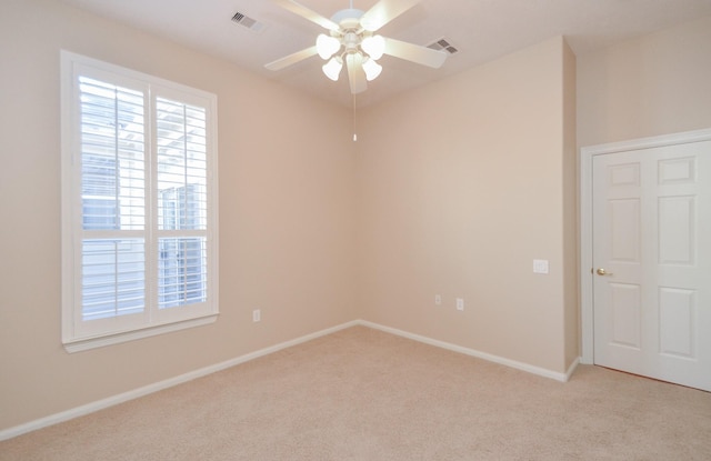 unfurnished room featuring a ceiling fan, light colored carpet, visible vents, and baseboards