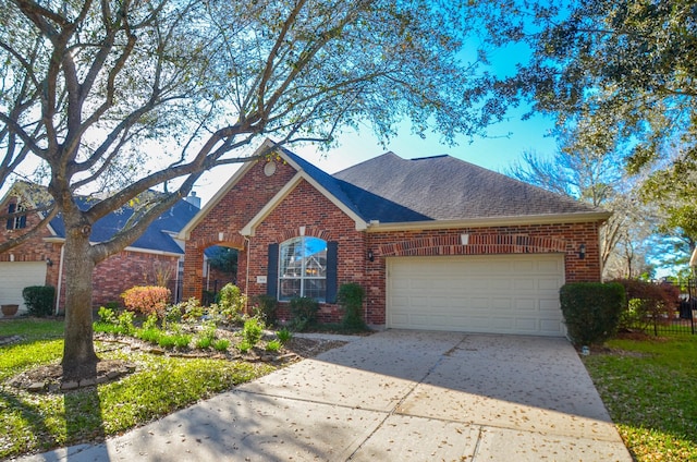 traditional-style house with a garage, brick siding, driveway, and roof with shingles