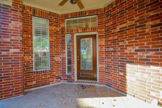 property entrance featuring brick siding and ceiling fan