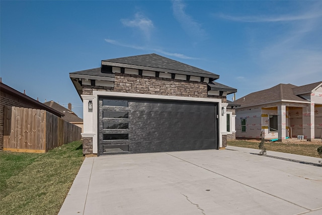 view of front of property featuring a garage, stone siding, and fence