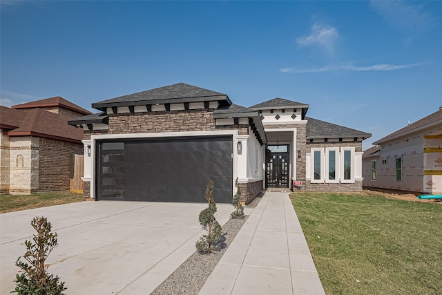 prairie-style home featuring a front yard, an attached garage, stone siding, and driveway