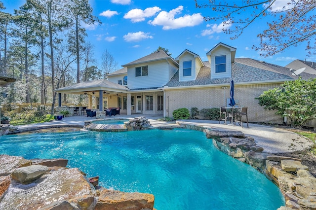 rear view of property with an in ground hot tub, a patio area, brick siding, and ceiling fan