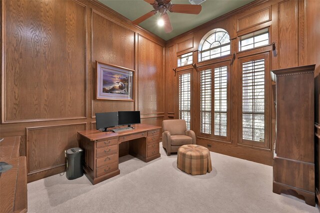 carpeted office with wooden walls, a decorative wall, and a ceiling fan