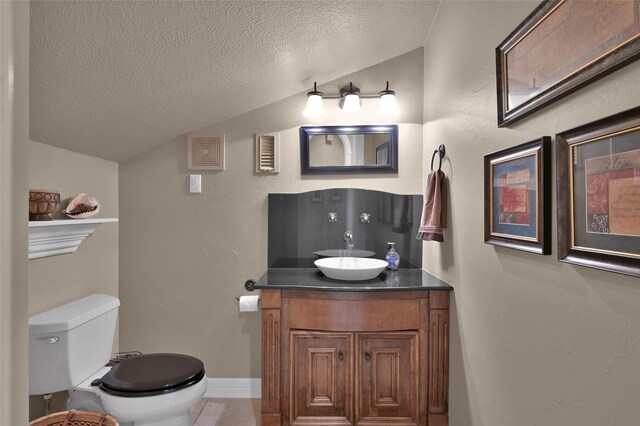 bathroom featuring toilet, a textured ceiling, vanity, and vaulted ceiling