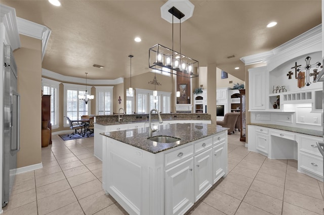 kitchen featuring a kitchen island with sink, light tile patterned flooring, crown molding, and a sink