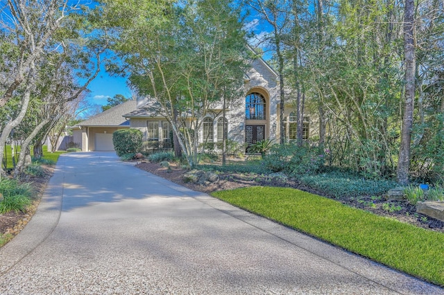 view of front of house featuring stone siding, driveway, and a garage