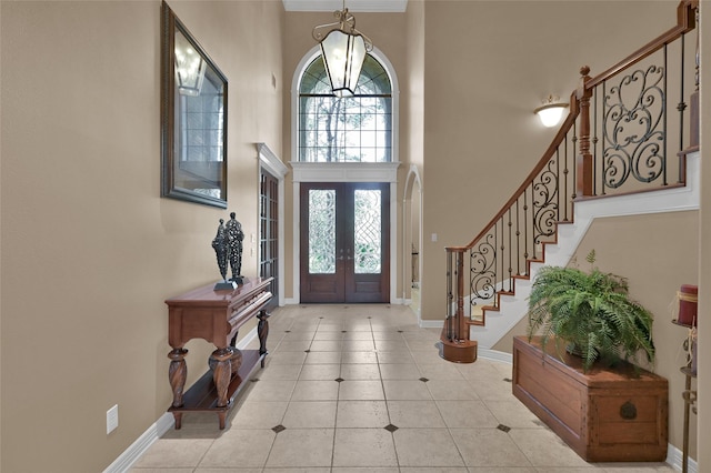 entrance foyer featuring baseboards, stairway, light tile patterned floors, french doors, and a towering ceiling